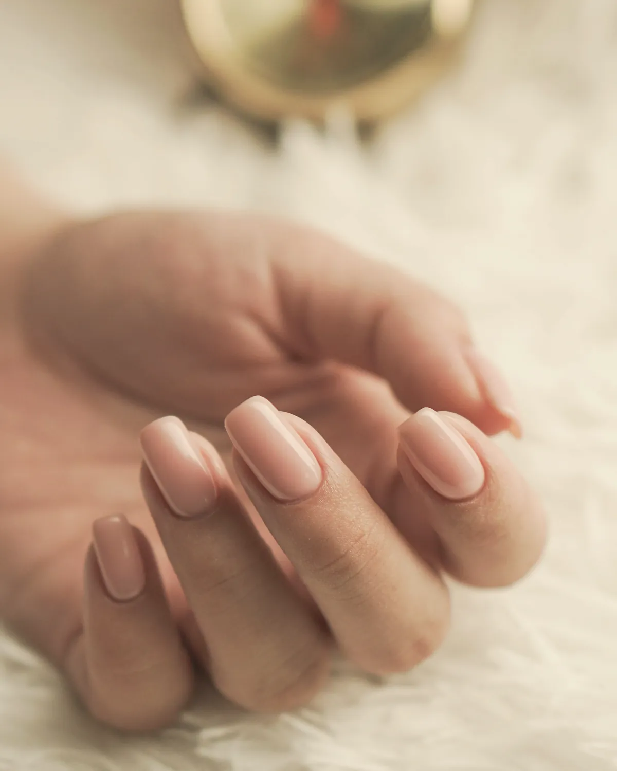 Soft almond nude manicure on a cream throw